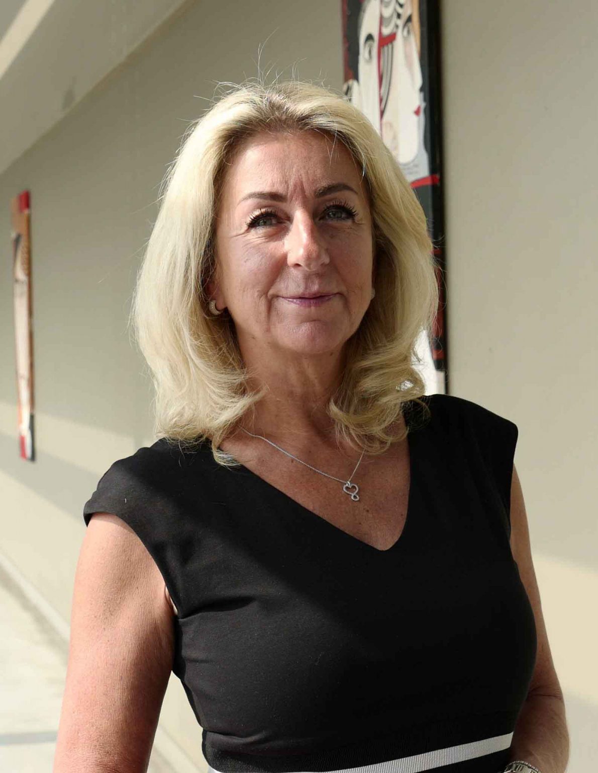 Elegante Frau in dunkler Bluse mit blondem, schulterlangem Haar